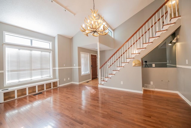 interior space with a chandelier, wood-type flooring, rail lighting, and high vaulted ceiling