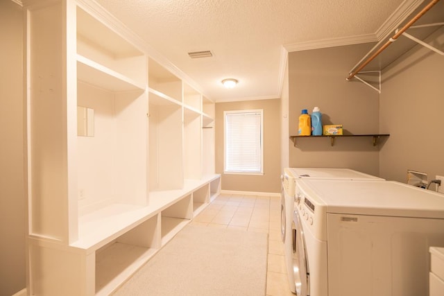 laundry area with light tile patterned floors, a textured ceiling, ornamental molding, and washing machine and clothes dryer