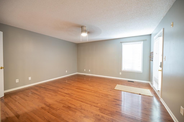 empty room featuring ceiling fan, a textured ceiling, and light wood-type flooring