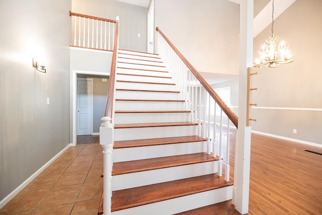 stairs featuring a chandelier, a high ceiling, and hardwood / wood-style flooring