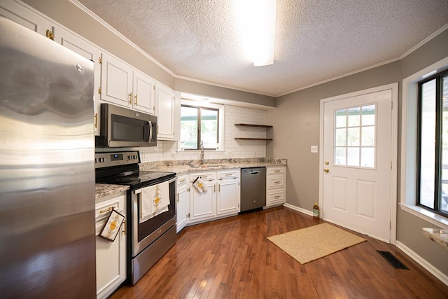 kitchen with a wealth of natural light, white cabinetry, dark hardwood / wood-style flooring, and stainless steel appliances