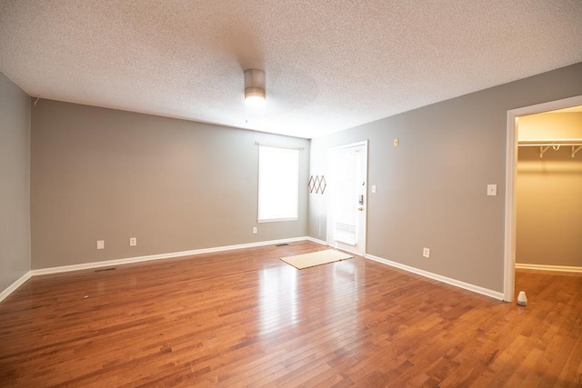 unfurnished room with wood-type flooring and a textured ceiling