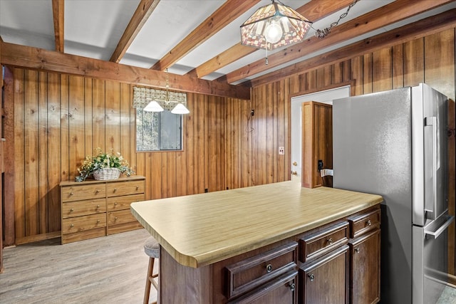 kitchen with decorative light fixtures, wooden walls, beam ceiling, fridge, and dark brown cabinets