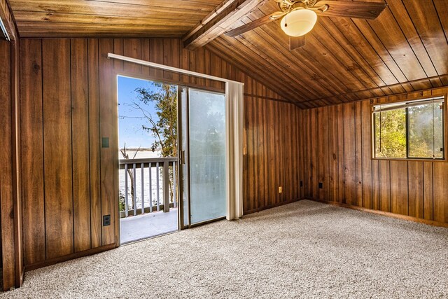 interior space with wood walls, ceiling fan, carpet flooring, and vaulted ceiling with beams