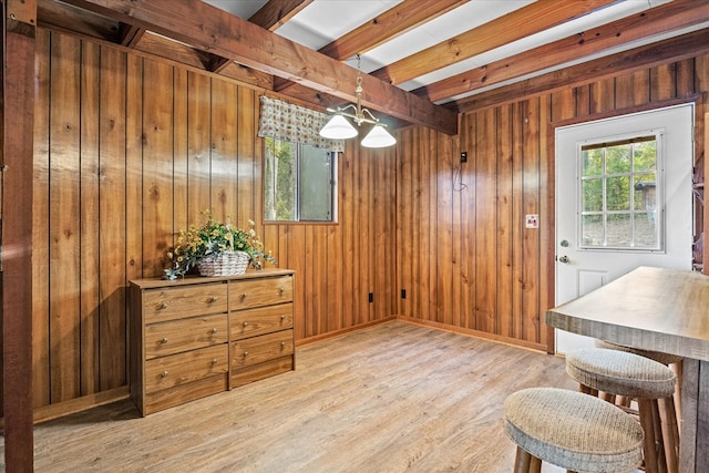 dining area featuring wood walls, beam ceiling, and light hardwood / wood-style flooring