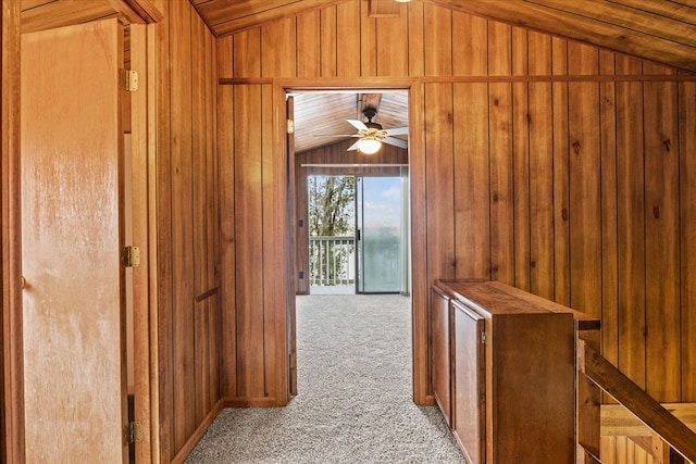 hall with lofted ceiling, light colored carpet, and wooden walls