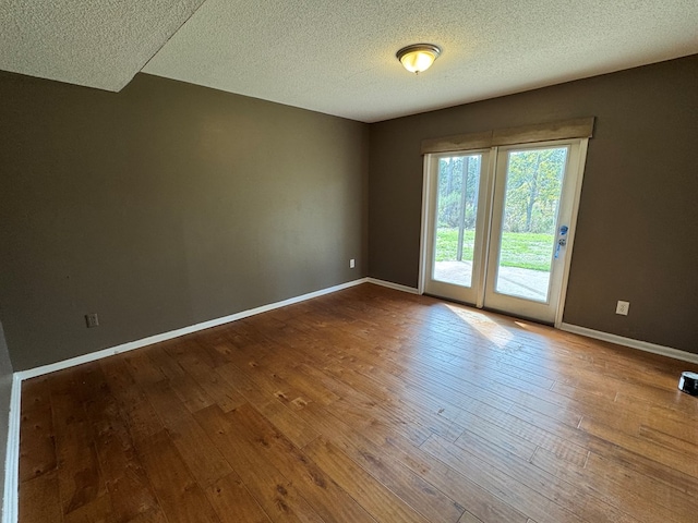 empty room featuring wood-type flooring and a textured ceiling