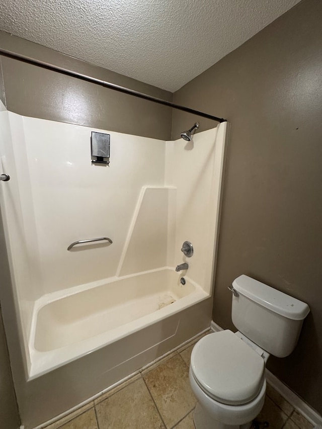 bathroom featuring a textured ceiling, bathing tub / shower combination, tile patterned flooring, and toilet