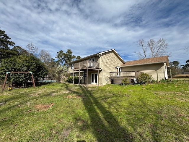 back of property featuring a lawn, a deck, and a playground