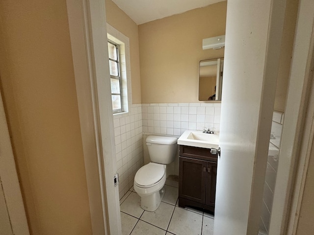 bathroom with tile patterned flooring, vanity, toilet, and tile walls