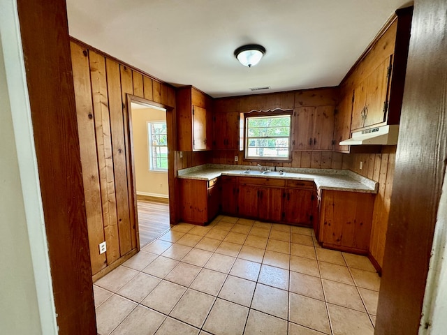 kitchen with wooden walls, sink, and light tile patterned floors