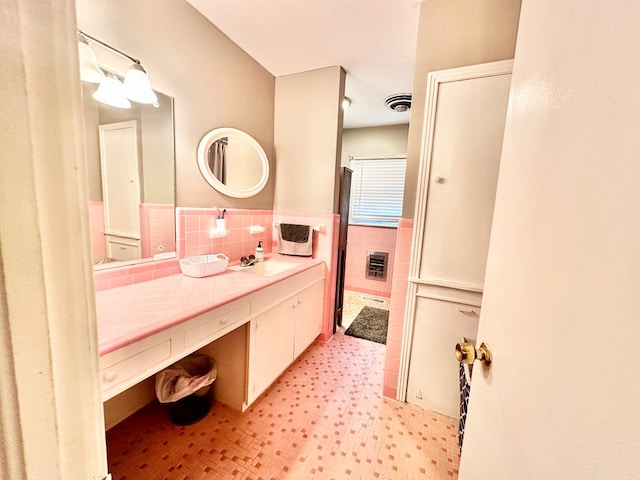 bathroom with heating unit, vanity, and tile walls