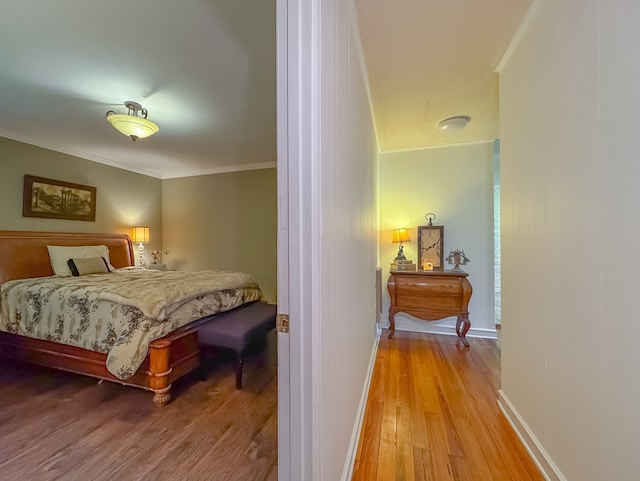 bedroom featuring crown molding, baseboards, and wood finished floors