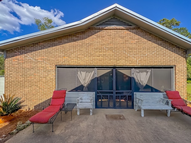 rear view of house featuring brick siding and a patio