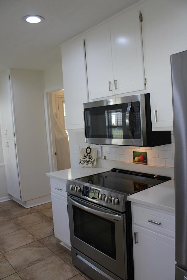 kitchen featuring stainless steel appliances, light countertops, and white cabinets