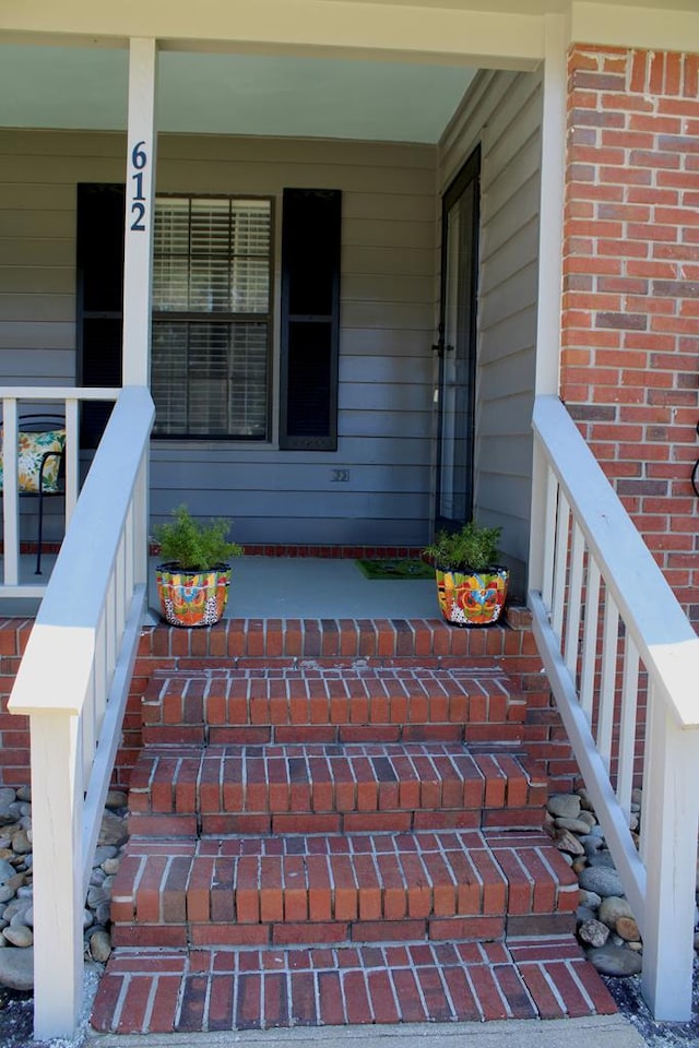 property entrance with covered porch and brick siding