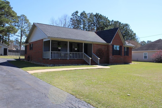 ranch-style home with a porch, brick siding, a shingled roof, a front lawn, and a chimney