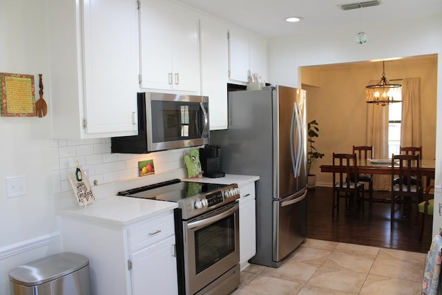 kitchen with hanging light fixtures, white cabinetry, appliances with stainless steel finishes, and light countertops