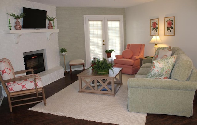 living area with a brick fireplace, dark wood finished floors, and french doors