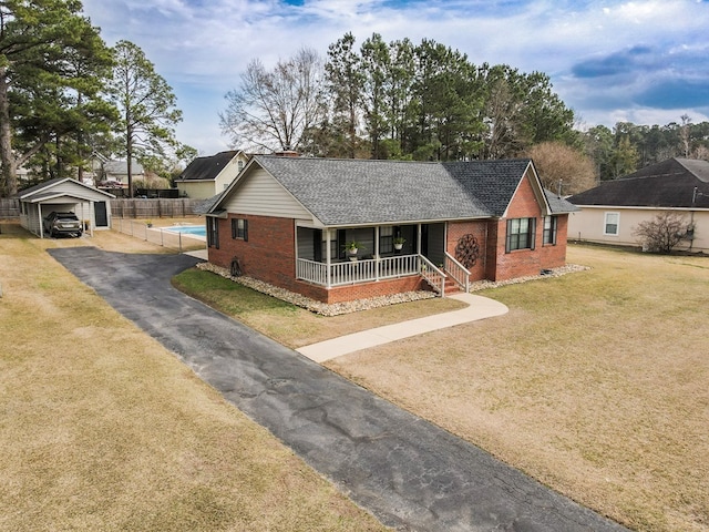 single story home featuring brick siding, roof with shingles, a porch, a front yard, and driveway