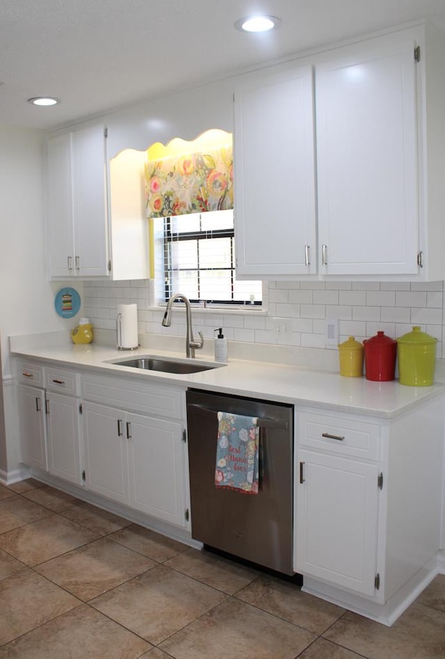 kitchen with tasteful backsplash, white cabinets, dishwasher, light countertops, and a sink