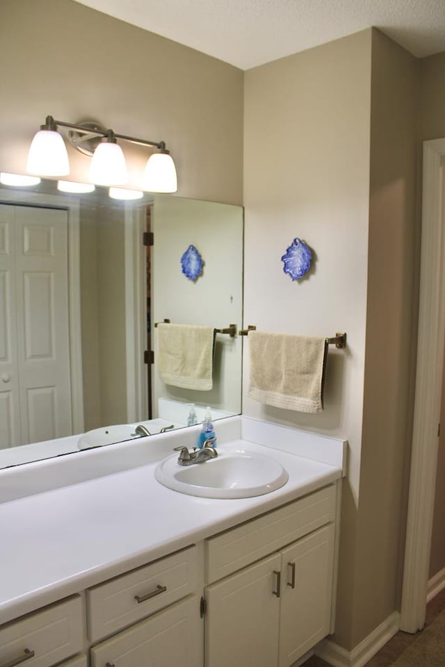 bathroom featuring a closet, baseboards, vanity, and a textured ceiling