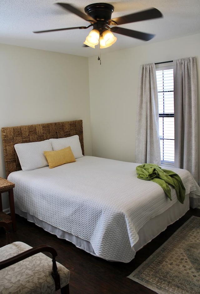 bedroom with dark wood-style floors, a textured ceiling, and a ceiling fan