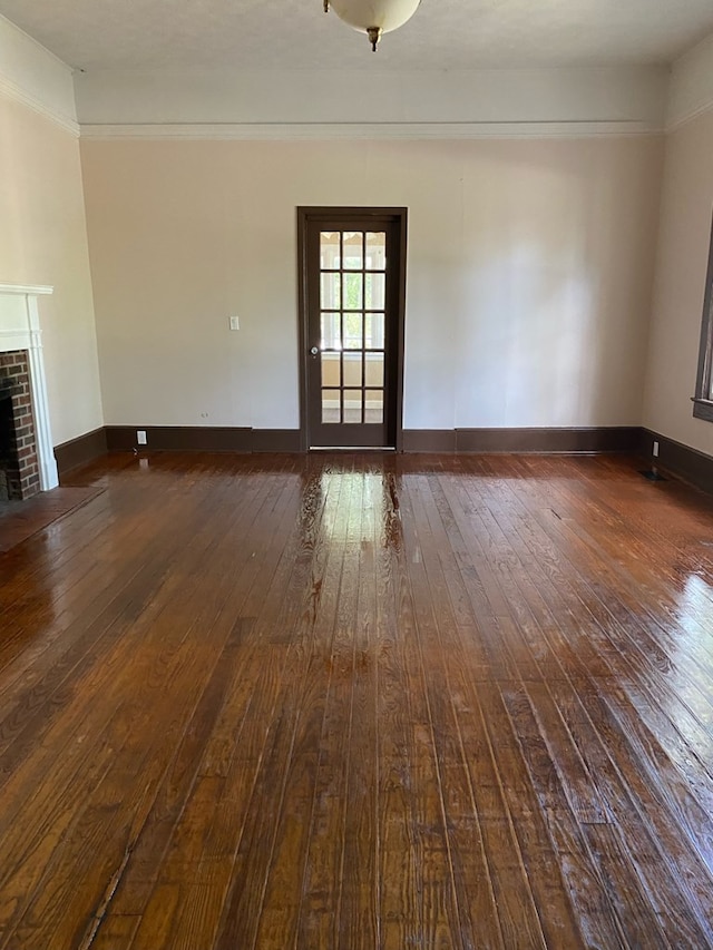 709 E College St, Bainbridge, GA 39817 - unfurnished living room with dark wood finished floors, a brick fireplace, and baseboards