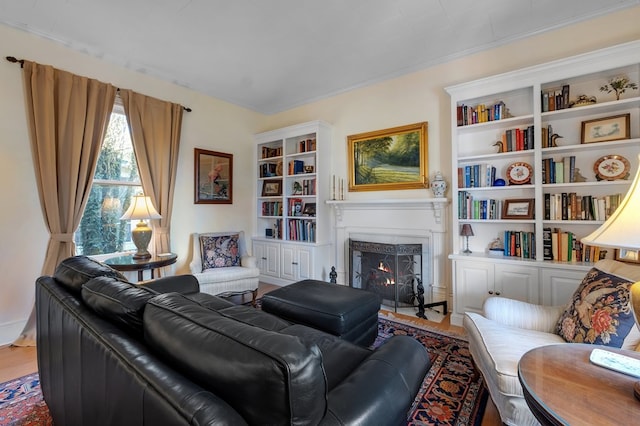 living room with built in features, wood-type flooring, and a high end fireplace