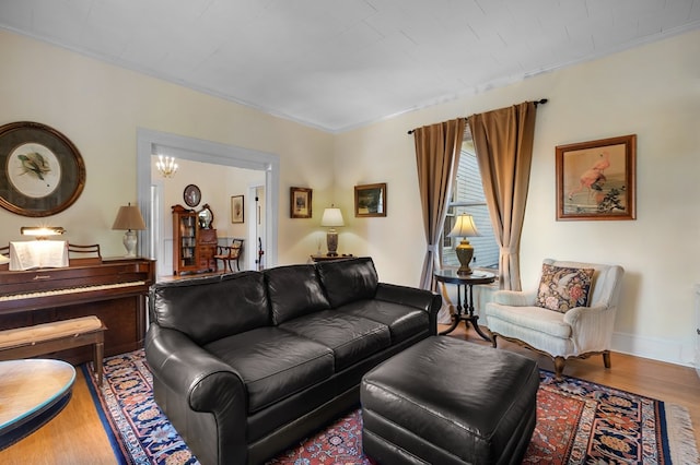 living room featuring wood-type flooring, a notable chandelier, and ornamental molding