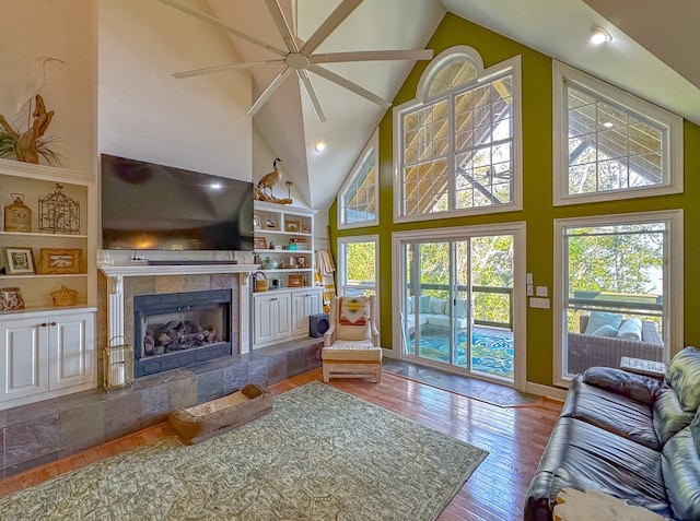 living room featuring a fireplace, ceiling fan, hardwood / wood-style floors, and high vaulted ceiling