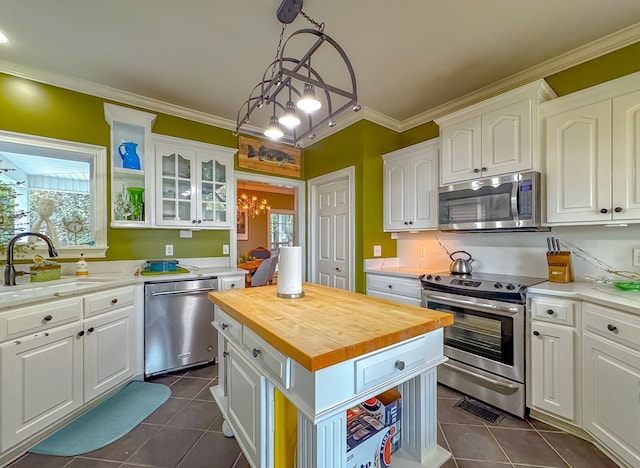 kitchen with a center island, sink, hanging light fixtures, appliances with stainless steel finishes, and white cabinetry