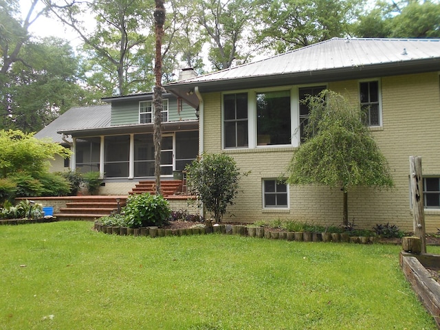 back of property with a sunroom and a yard