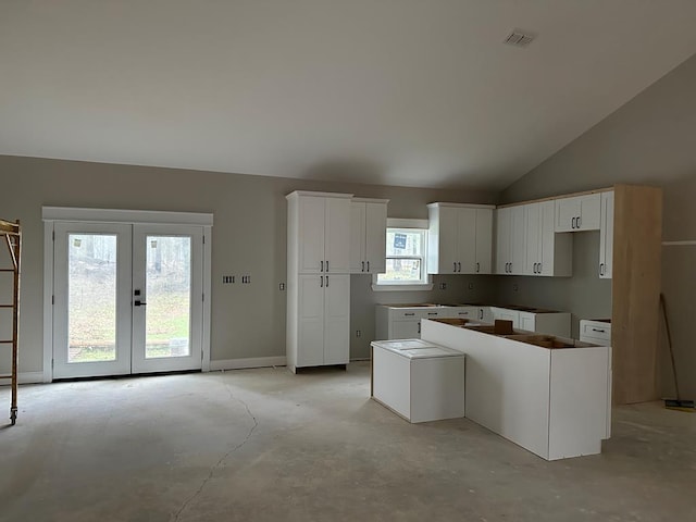 kitchen with white cabinetry, french doors, lofted ceiling, and a center island