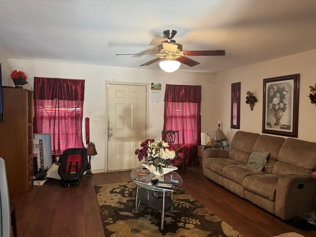 living room featuring ceiling fan, dark hardwood / wood-style flooring, and a textured ceiling