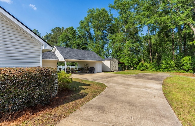 view of side of property featuring concrete driveway, an outbuilding, a lawn, and a storage unit