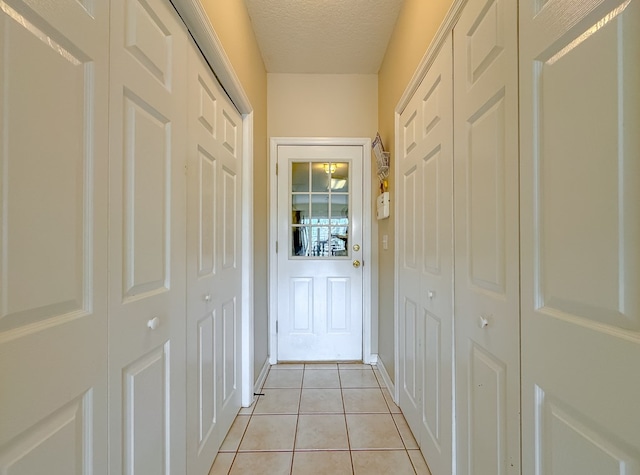 corridor with a textured ceiling and light tile patterned flooring