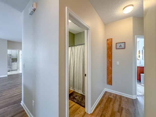 corridor with a textured ceiling and wood-type flooring