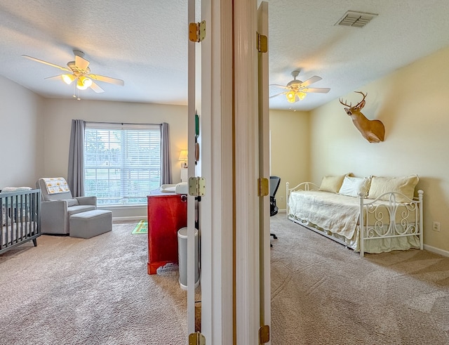 bedroom with ceiling fan, carpet floors, and a textured ceiling