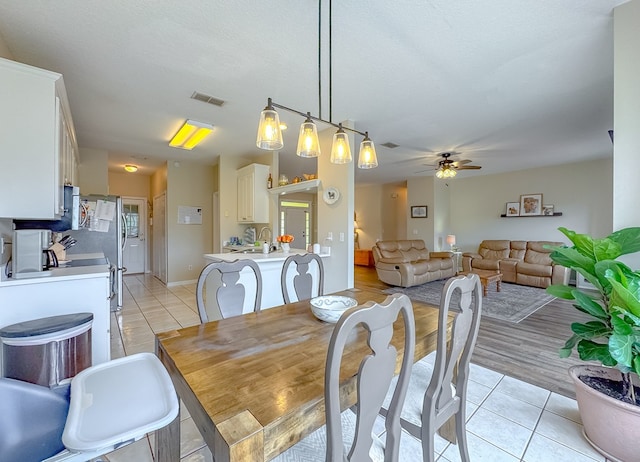 tiled dining room with a textured ceiling, sink, and ceiling fan