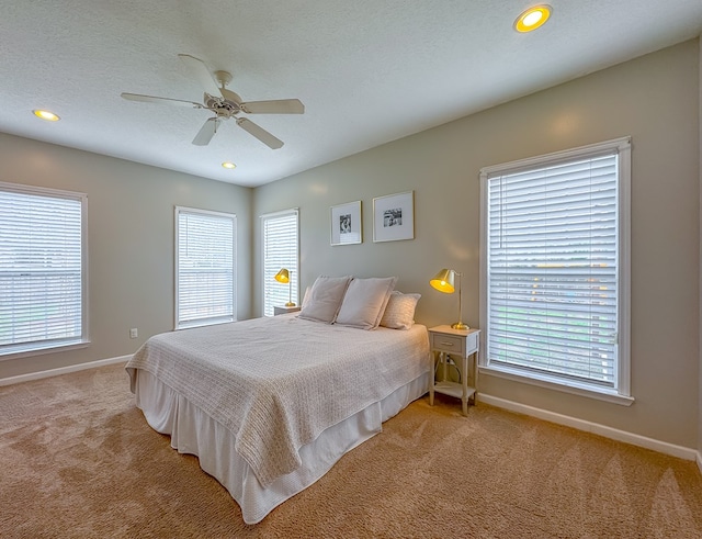 carpeted bedroom featuring multiple windows, ceiling fan, and a textured ceiling