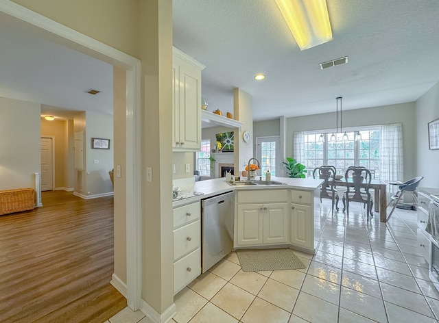 kitchen with a textured ceiling, stainless steel dishwasher, pendant lighting, sink, and kitchen peninsula