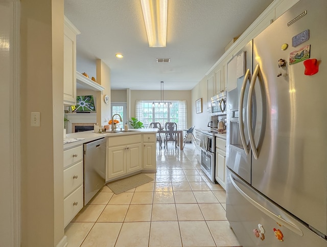 kitchen featuring stainless steel appliances, decorative light fixtures, sink, white cabinetry, and kitchen peninsula