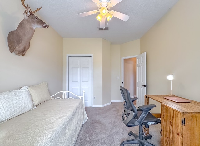 carpeted bedroom featuring a closet, ceiling fan, and a textured ceiling