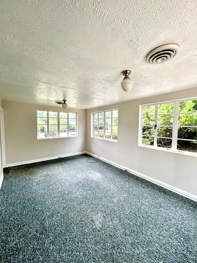 356 E Main St, Colquitt, GA 39837 - empty room featuring baseboards, a textured ceiling, and dark colored carpet