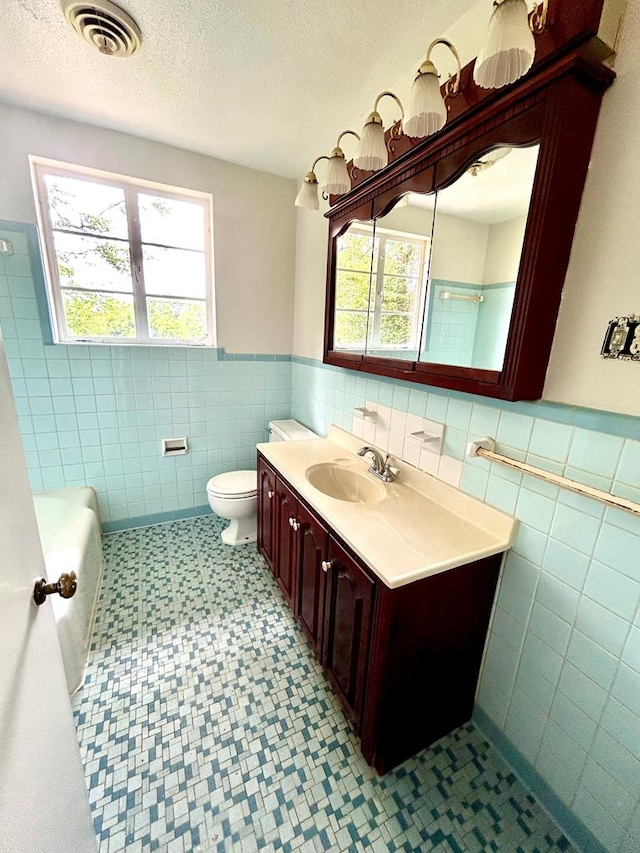 356 E Main St, Colquitt, GA 39837 - bathroom with tile walls, wainscoting, toilet, a textured ceiling, and vanity