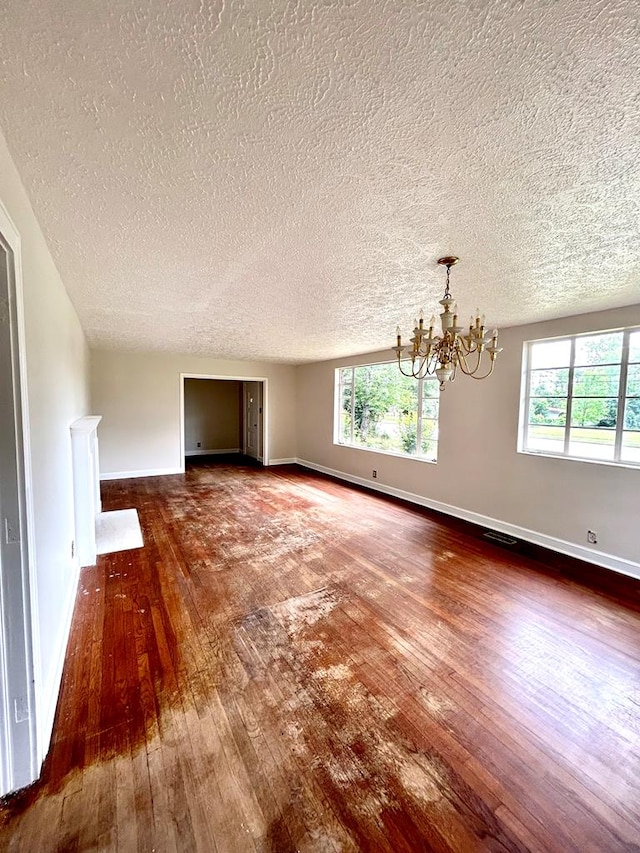 356 E Main St, Colquitt, GA 39837 - unfurnished living room with a chandelier, dark wood-style flooring, a textured ceiling, and baseboards