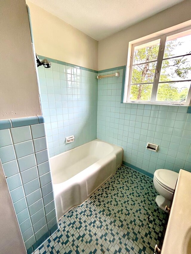 356 E Main St, Colquitt, GA 39837 - bathroom featuring tile walls, toilet, a wainscoted wall, and bathing tub / shower combination
