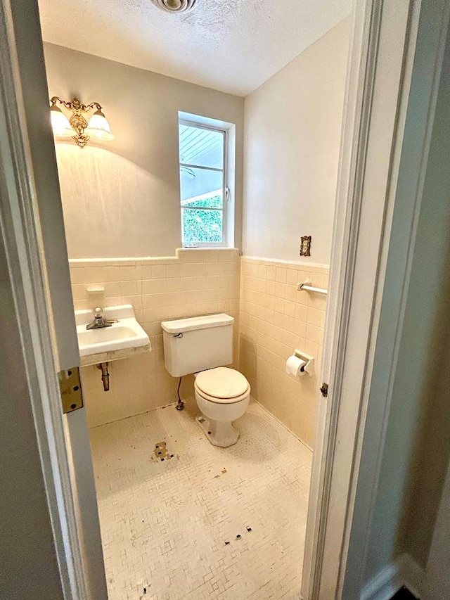 356 E Main St, Colquitt, GA 39837 - bathroom with tile walls, toilet, a wainscoted wall, a sink, and a textured ceiling