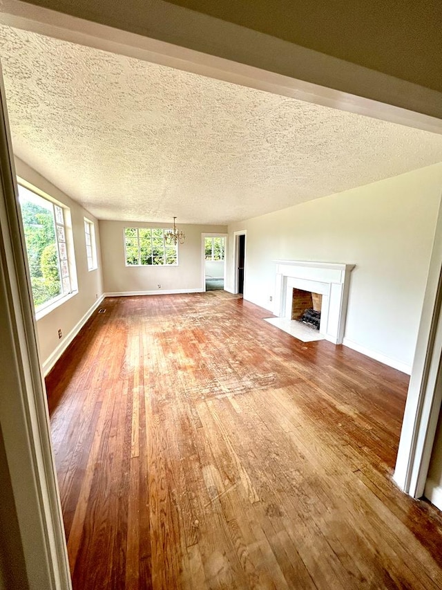 356 E Main St, Colquitt, GA 39837 - unfurnished living room with hardwood / wood-style flooring, a chandelier, a fireplace with flush hearth, and baseboards